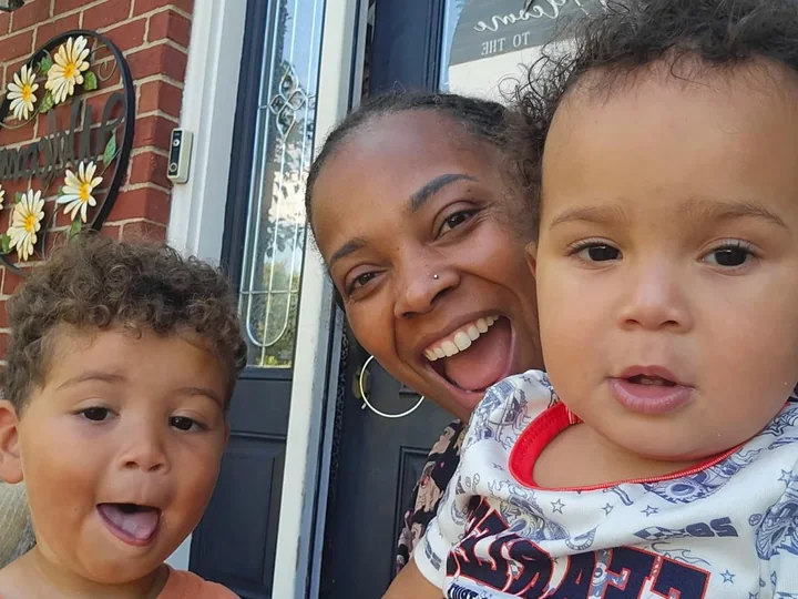 Colia Wilson laughing at her front door with a toddler and a baby.